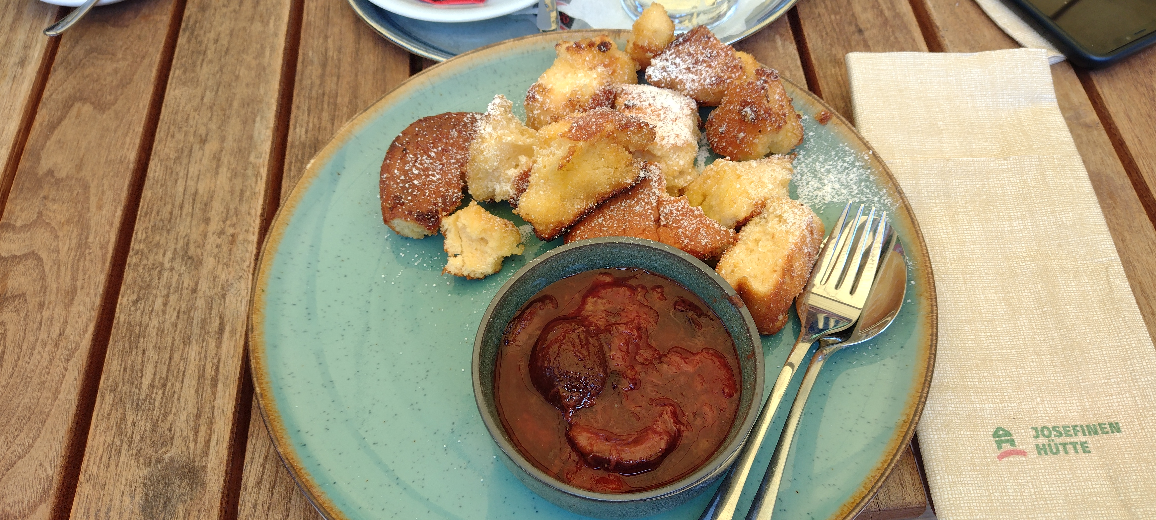 Kaiserschmarrn with plum sauce on a turquoise plate on top of a garden table